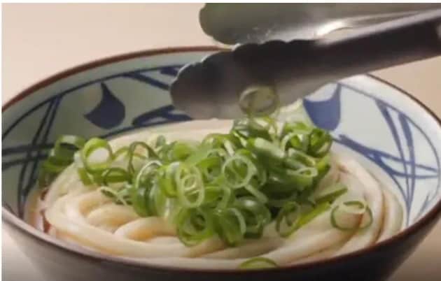 丸亀製麺のうどんにトッピングのねぎをのせている