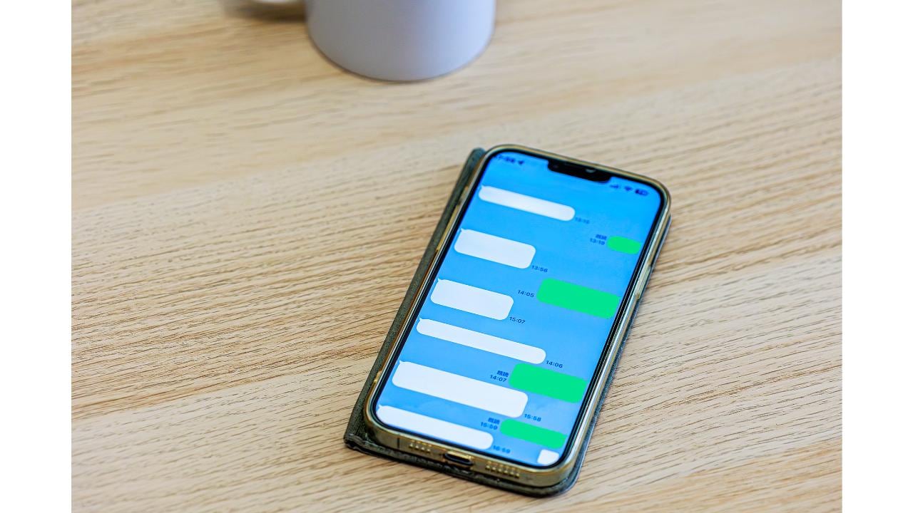 机の上に置かれたメッセージアプリのトーク画面を表示しているスマートフォン