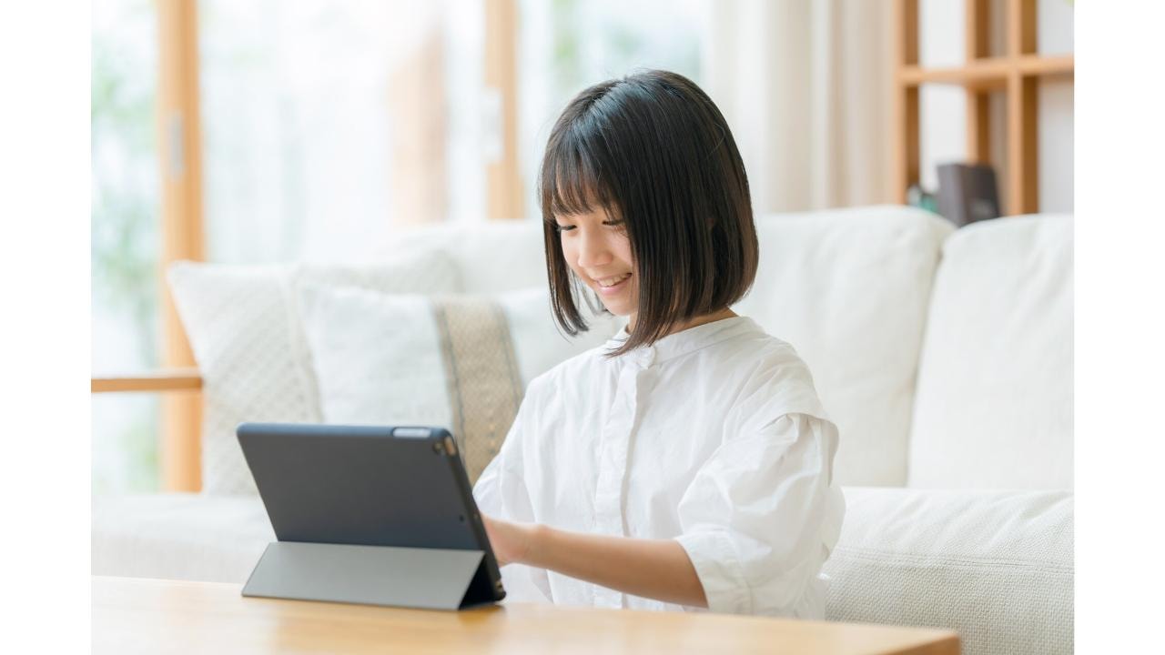 リビングでタブレットを操作して学習・閲覧する女の子