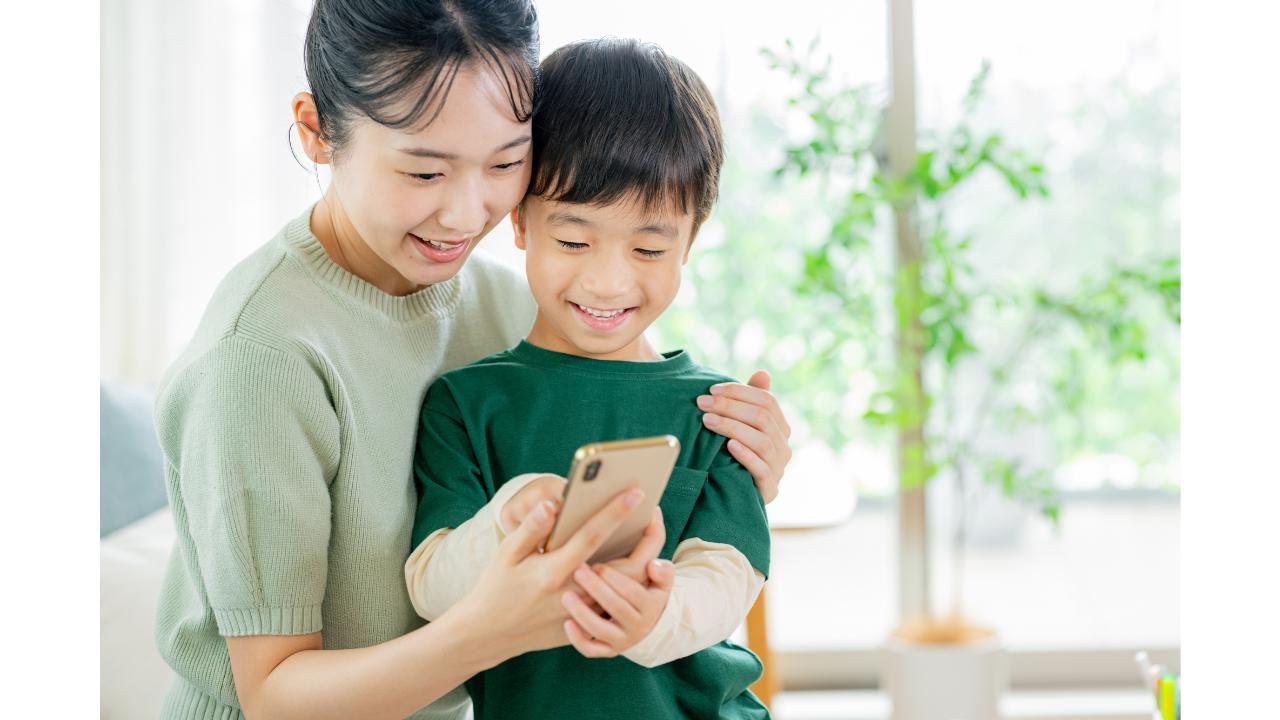 親子で寄り添いながらスマートフォン画面を見る母親と男の子