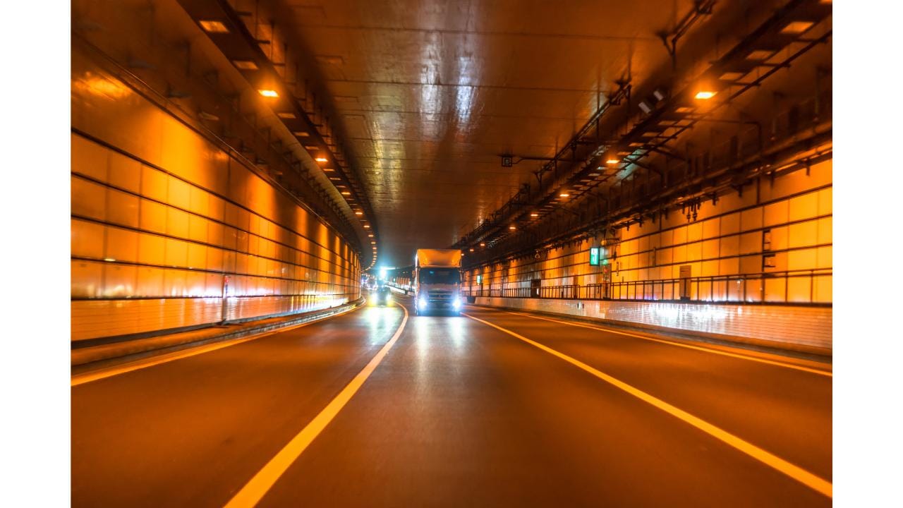 オレンジ色の照明に照らされた道路トンネル内を走る車