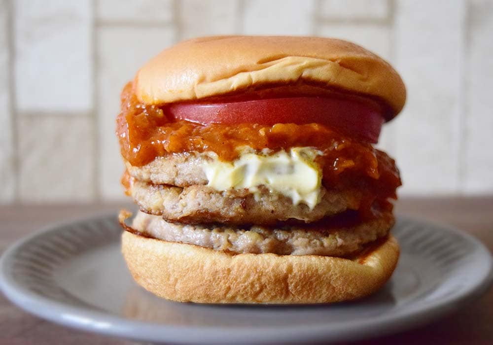 ハンバーガーパティ3枚にオニオン、ミートソース、トマトなどがサンドされています。