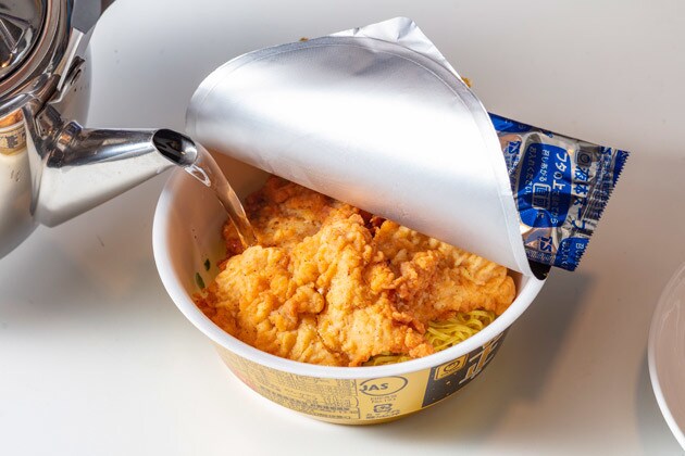 （１）注ぐ！　マルちゃん正麺のフタを開け、かやくと一緒にケンタッキーのチキンも豪快に投入し、その上から熱湯を注ぐ。チキンの脂分とスパイスが染み出てスープがこってり激ウマ化！