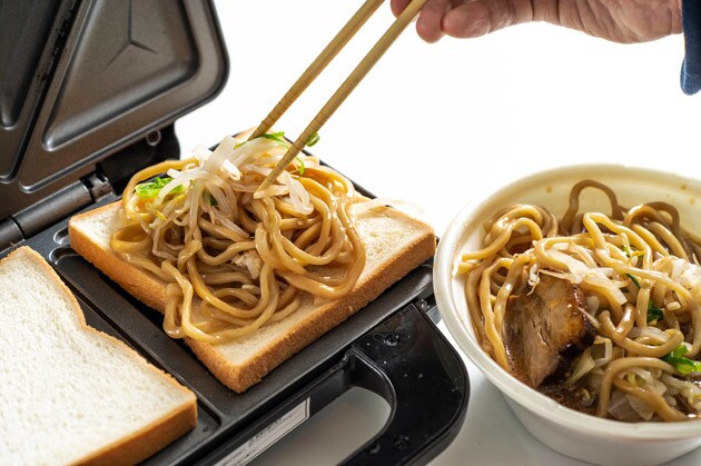 （１）のせる！　ホットサンドメーカーに食パンをのせ、その上に豚ラーメンの麺と野菜をたっぷりのせる。さらに焼き豚切り落しもマシマシし、豚ラーメンのスープを大さじ１杯程度かけよう