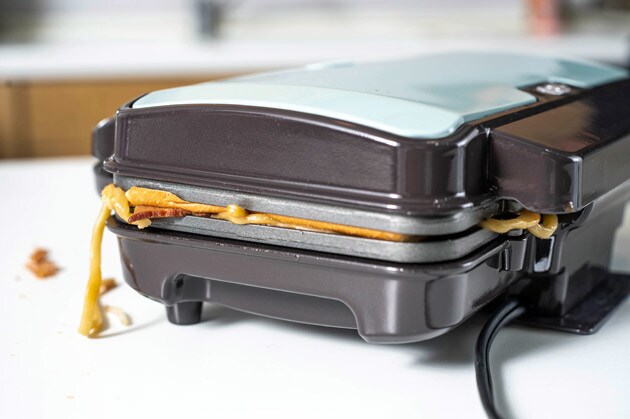 （２）焼く！　食パンをもう１枚のせたら、強引にホットサンドメーカーのフタを閉めて焼き上げる。多少はみ出ても問題ないが、機械が壊れないように注意。まねする場合は自己責任で！