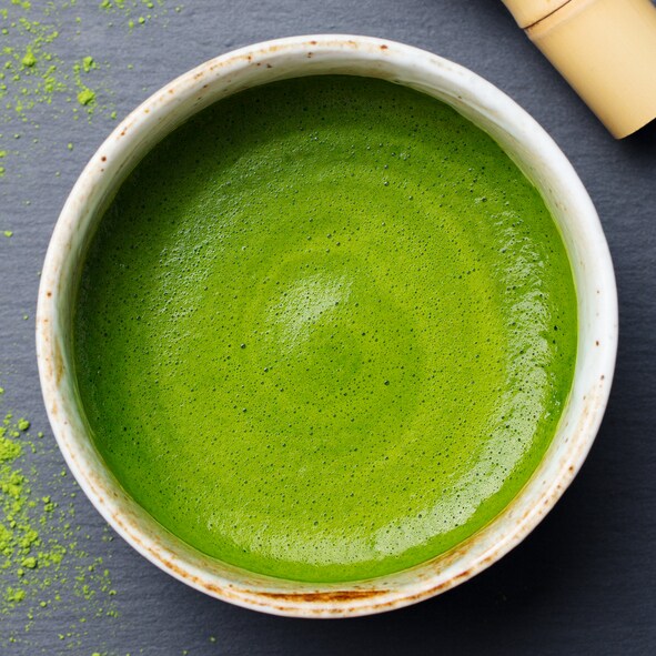 Matcha, green tea latte in a cup. Grey stone background. Top view.