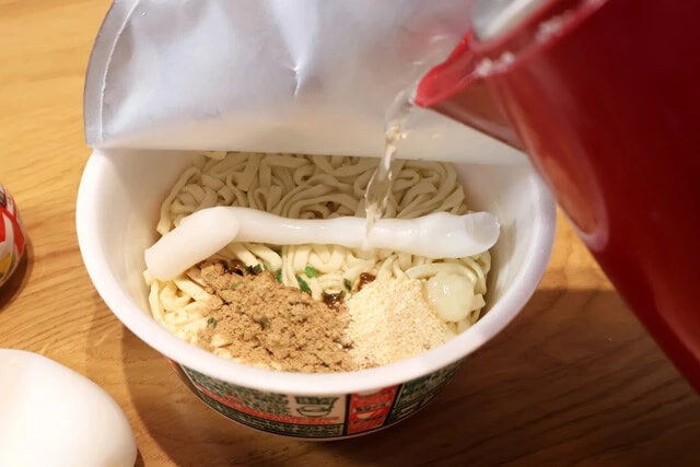 （３）熱湯！　続いて熱湯をカップ内側の線まで注ぐが、ラードの上に熱湯をかけるのがおいしく作るコツ。直接かけることでラードをしっかり溶かそう。あとはフタをして5分待つ