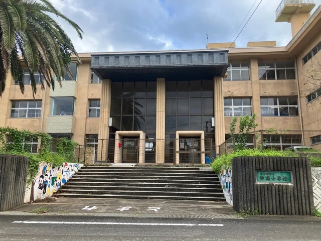 2015年度に閉校した神浦小学校は、九電工が借り受け事務所として使用。教室はそのまま残され、下請けの建設会社も入居。校庭は重機の駐機場に