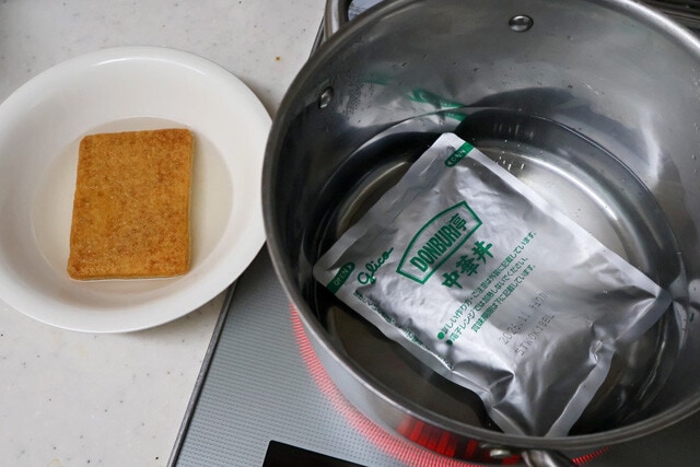 (1)湯煎! お湯を沸騰させ、レトルト中華丼の具を温める。同時にどん兵衛のお揚げを食器に移し、熱湯を注いで戻す。お揚げは柔らかく戻ったら水気を軽く切り、ひと口大にカットする