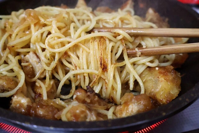 (4)焦がす! パスタにソースが絡んで茶色くなってきたら火力を上げて麺を焦がす。トンテキは焦げないようにパスタの上に避難させておくとよい。麺の表面がカリッとしてきたら完成だ!