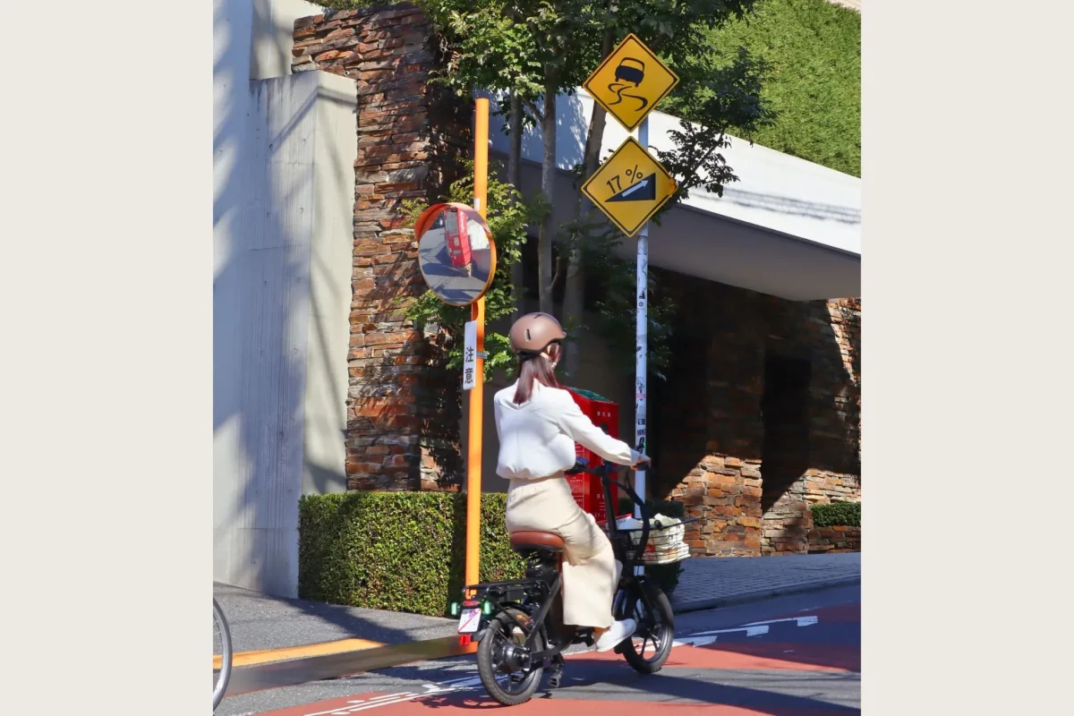 電動自転車に乗る女性と勾配を示す道路標識