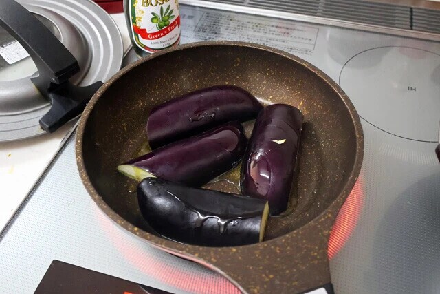 (2)蒸し焼き! 熱したフライパンにナスを並べ、オリーブオイルをたっぷりとかける。ナスが油を吸収したら水を少し垂らしてからフライパンにフタをし、蒸し焼きにしてしっかりと火を通そう