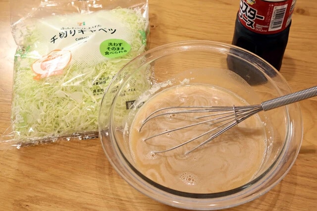 （２）生地！　薄力粉、ウスターソース、水をボウルに入れて泡立て器でしっかり混ぜる。薄力粉のダマがなくなったらキャベツも投入。キャベツはコンビニのパック野菜を使うと便利だ