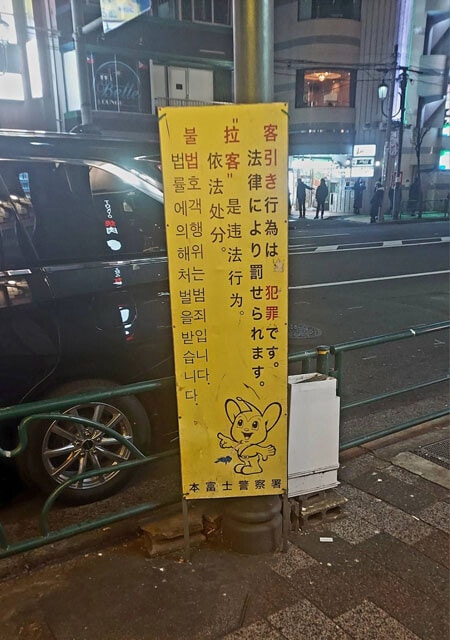 中国語と韓国語で客引き行為への警告が書かれた看板。夜になると日本人を含め、さまざまな国の女性たちが街の通りに並ぶ