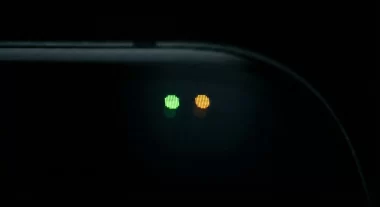 iPhoneのステータスバーに表示される緑色とオレンジ色のプライバシーインジケータードットのクローズアップ画像