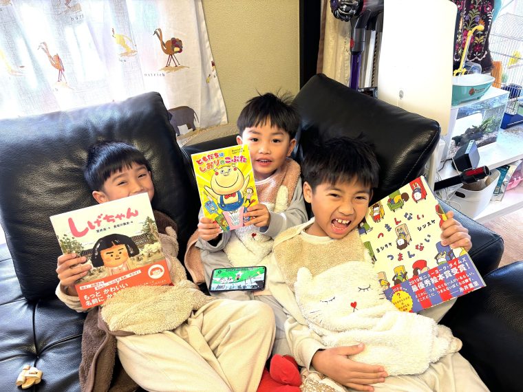 母子家庭の子らに新本を贈る　志継ぐ元出版社社長の岩崎弘明さん 2025年12月に贈られた新品の本を手にして喜ぶ子どもたち＝ハーモニーネット未来提供