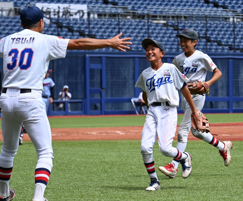 五回、ピンチを脱して多賀少年野球クラブの辻監督に迎えられる岡本（15日、ハードオフ新潟＝松﨑航大）