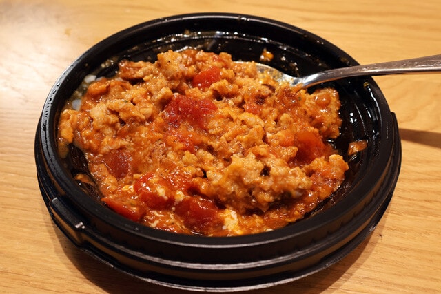 （１）潰す！　うまトマハンバーグの温玉を取り出したら、スプーンなどを使ってハンバーグ全体をグニグニと潰し、うまトマソースとよく混ぜてミートソースにしよう（温玉は不使用）