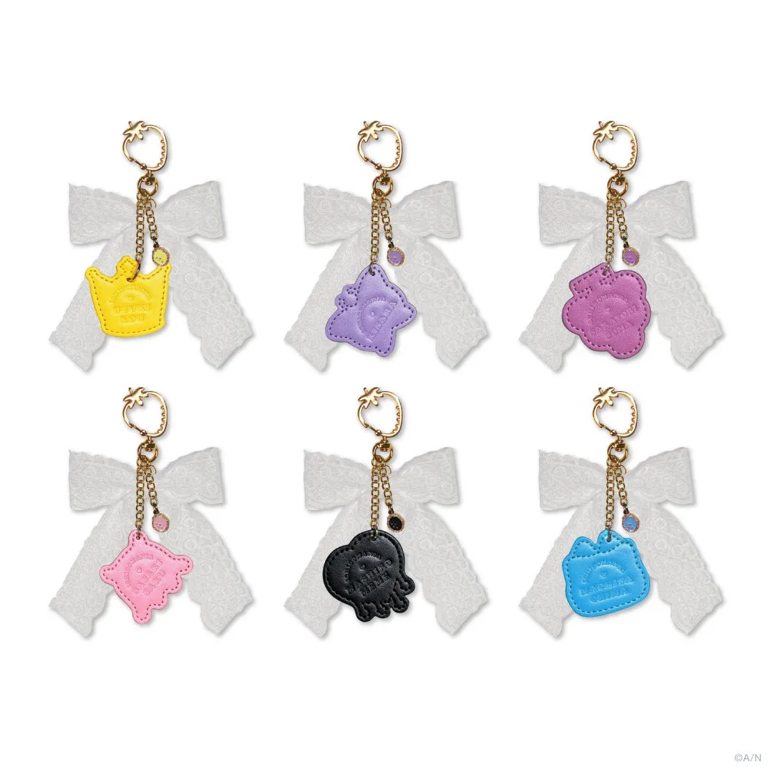キーホルダーが6つ並んだ写真。それぞれ異なる色とデザインで、リボンとチェーンが付いている。