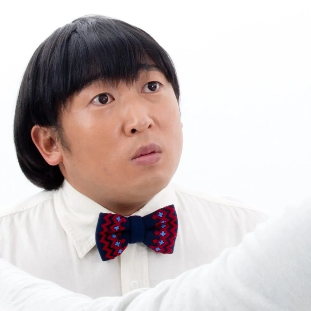 男性が蝶ネクタイと白いシャツを着て、見上げている写真です。