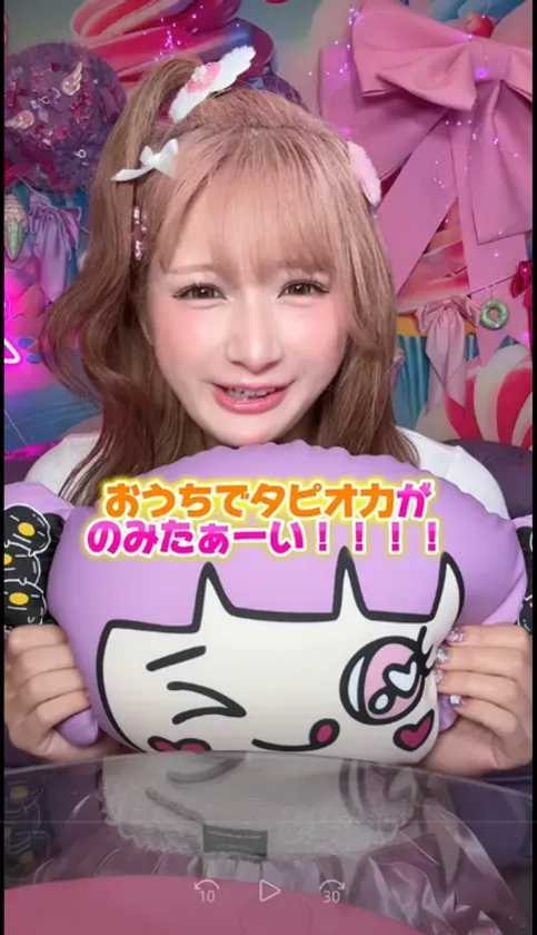 女性がキャラクターのクッションを持って笑顔で写っている写真です。