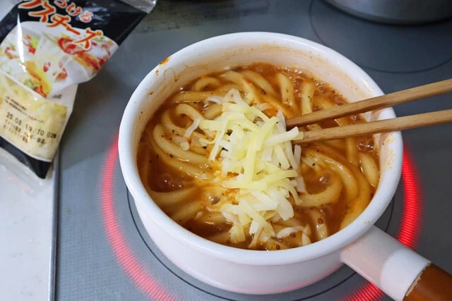 （４）チーズ！　麺がスープを吸収したら火力を弱め、とろけるチーズを適量入れる。ほんのり溶け始めたら火を止めて食器に移そう。スープをよく吸ったうどんは完全に極太生パスタ！