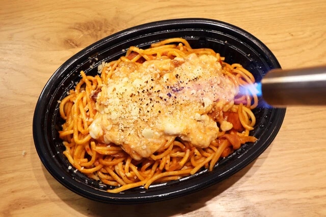 （３）バーナー！　（２）の手順が終わったらそのまま食べても十分すぎるほどウマいが、ガスバーナーがあるならナポリタンに付属の粉チーズをかけてからあぶると一体感が増すのでオススメだ！