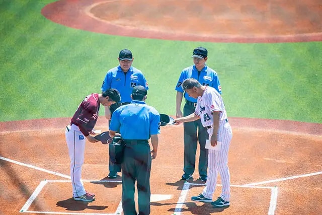 メンバー表を交換する、楽天の渡辺直人2軍監督（左）とヤクルトの池山2軍監督（右）。