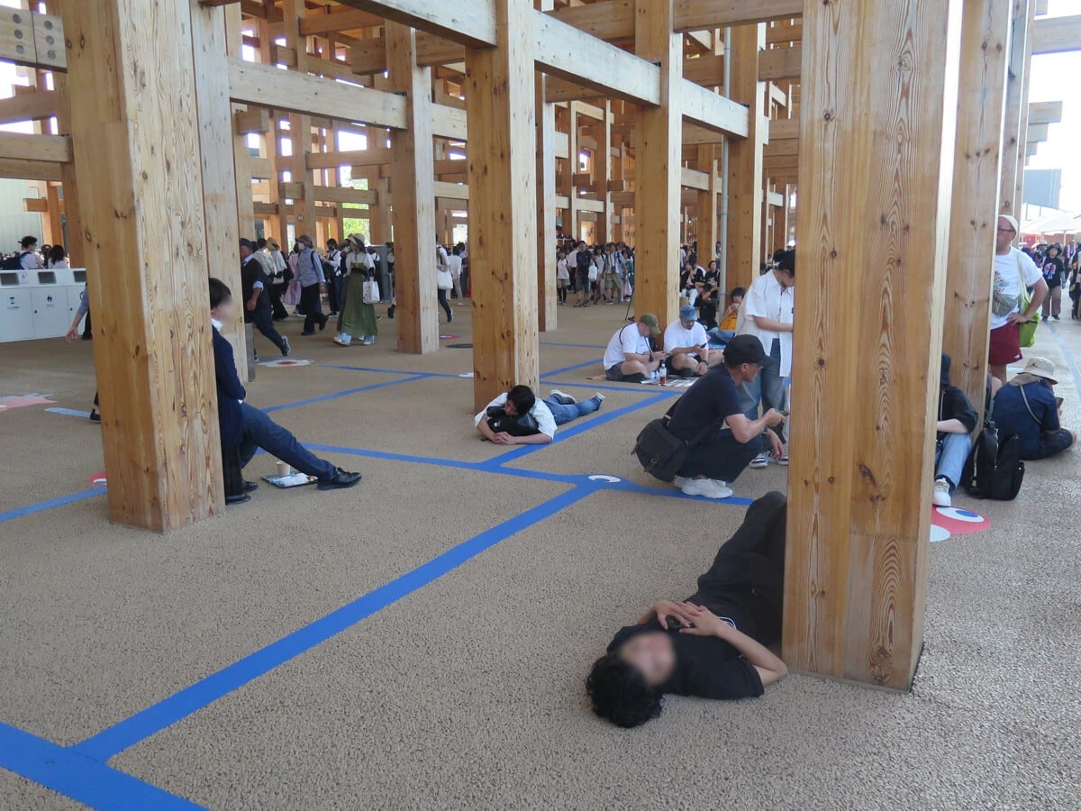 午後3時過ぎ、暑さでやられた来場者が次々とダウン。大屋根リング下では、寝そべる人の姿が目立ち始める