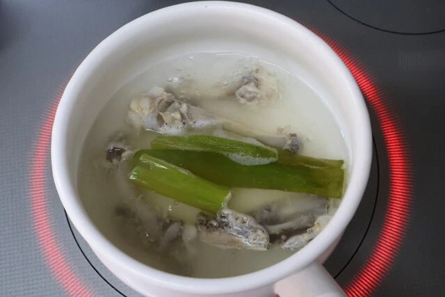 （２）だし！　軽く水洗いした骨を2分間煮込み、お湯を捨て再び骨を流水で洗う（湯引き）。その後、水と骨を鍋に入れ、中火で60分ほど煮出す。ネギの青い部分もできれば入れよう
