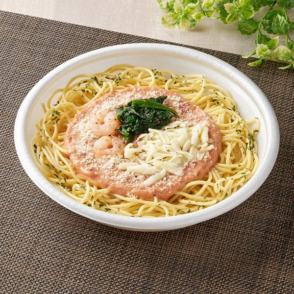 エビとほうれん草が入ったパスタが白い容器に入っている写真です。