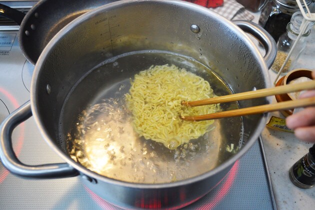 （２）ゆでる！　もうひとつの鍋でたっぷりのお湯を沸かし、辛辛魚の容器から麺だけを取り出して４分ゆでよう。ここではかやくを入れないので間違えないこと。ゆで終えたら麺をザルにあける